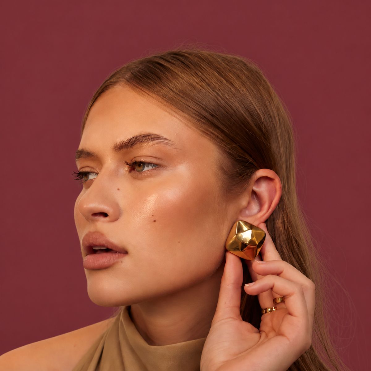Gold-Tone Triangle Earrings — muted burgundy background