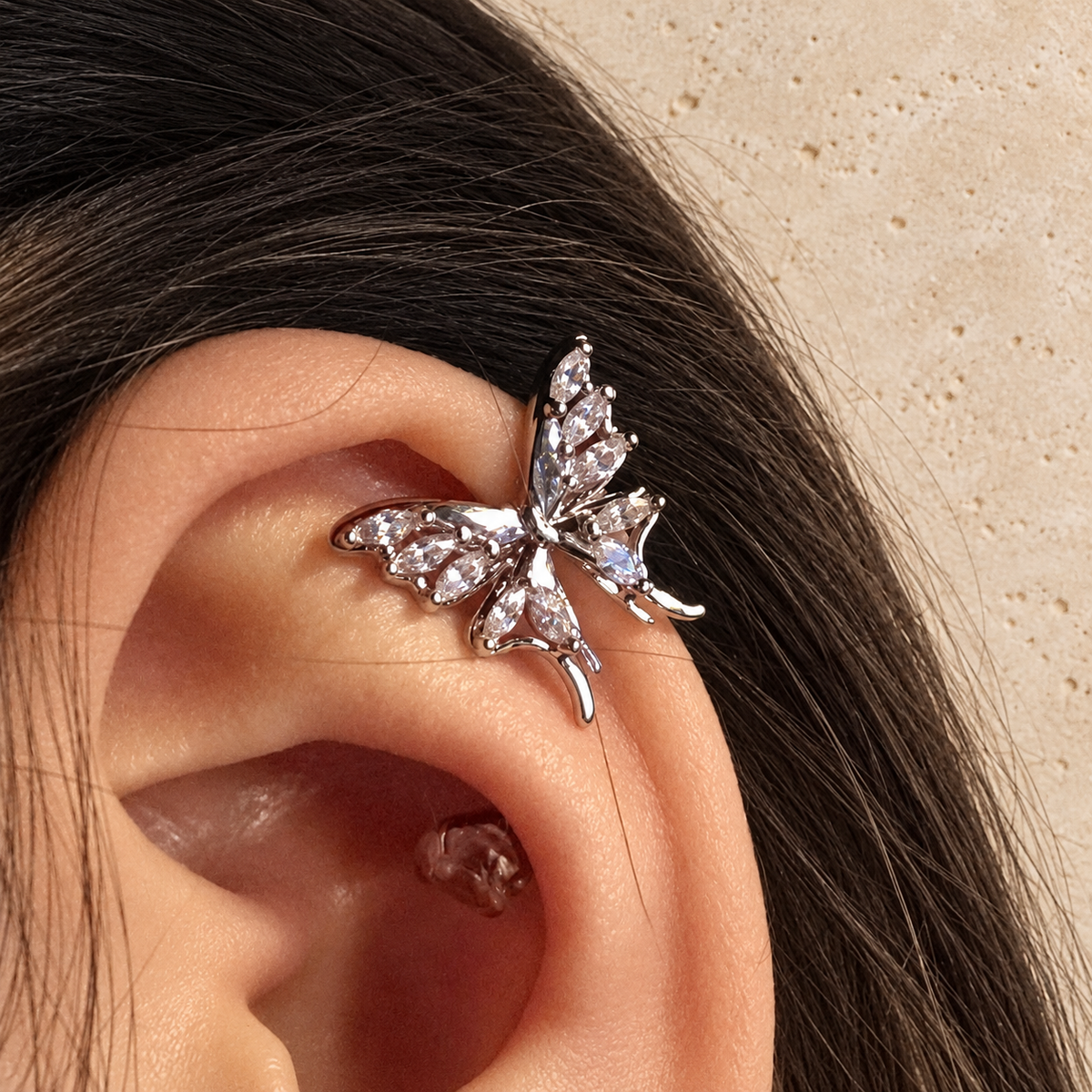 Gold Butterfly Ear Clip — pale beige natural stone background