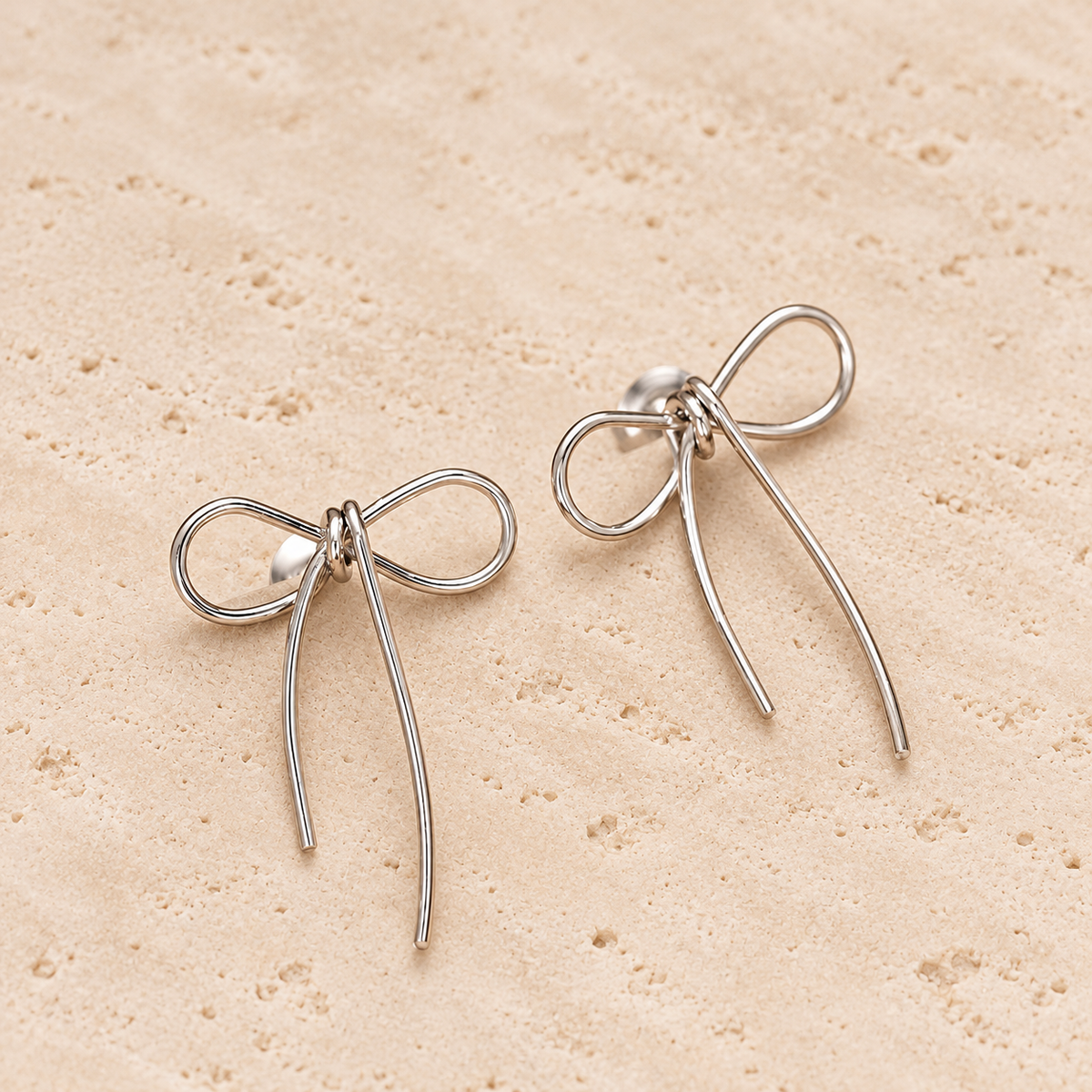 Gold Bow Studs — pale beige natural stone background