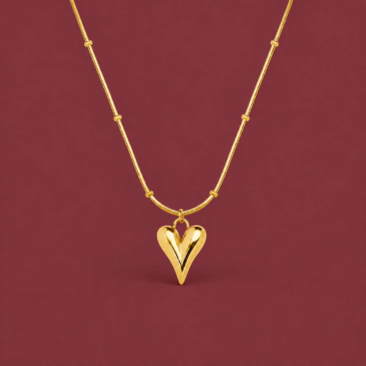 Gold-Tone Heart Pendant — muted burgundy background