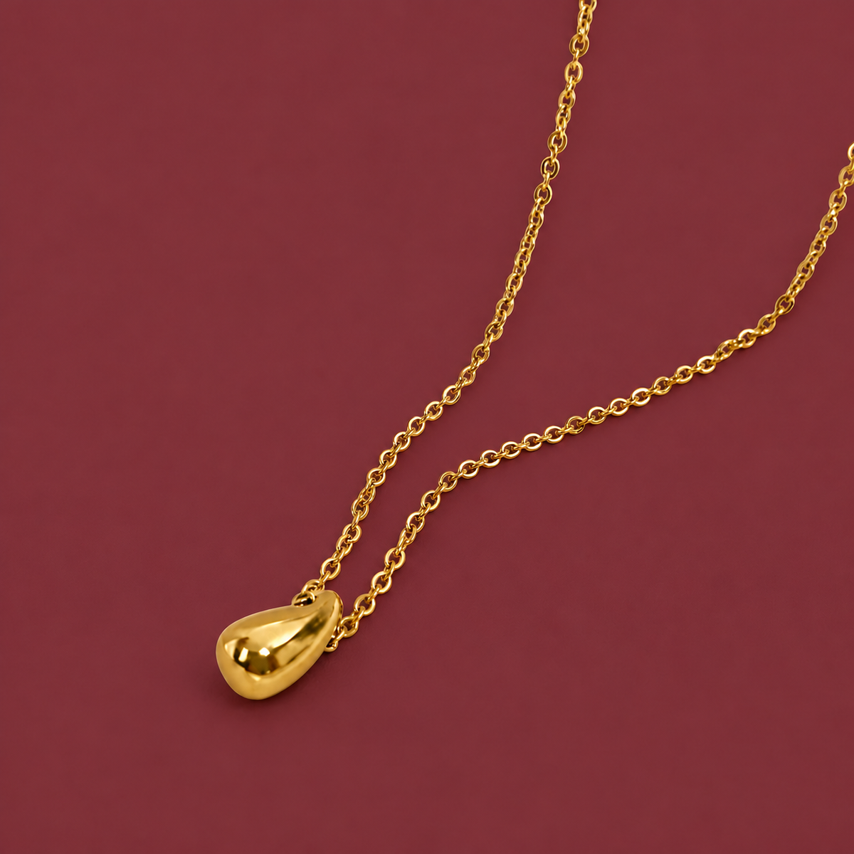 Gold-Tone Waterdrop Necklace — muted burgundy background