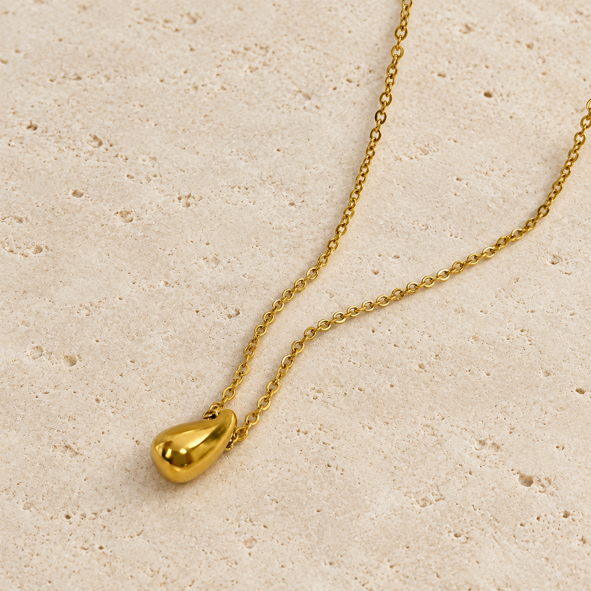 Gold Waterdrop Necklace — pale beige natural stone background