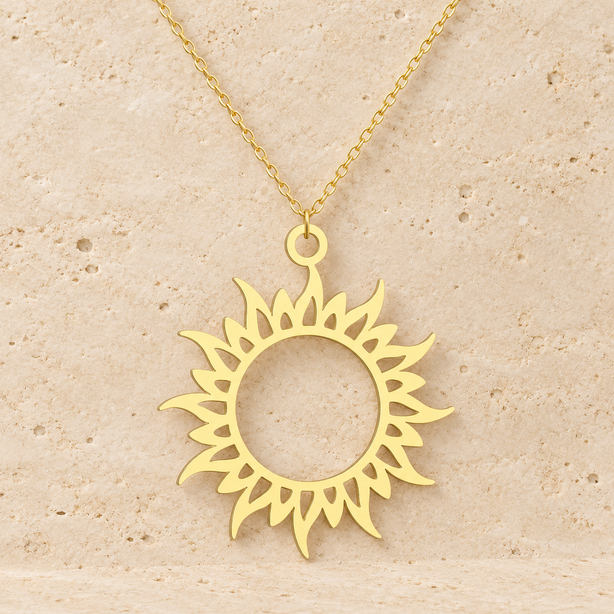 Gold Sun Symbol Necklace — pale beige natural stone background