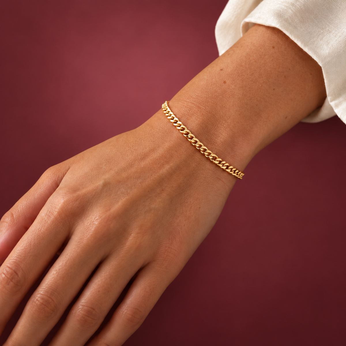 Gold-Tone Cuban Link Bracelet — muted burgundy background