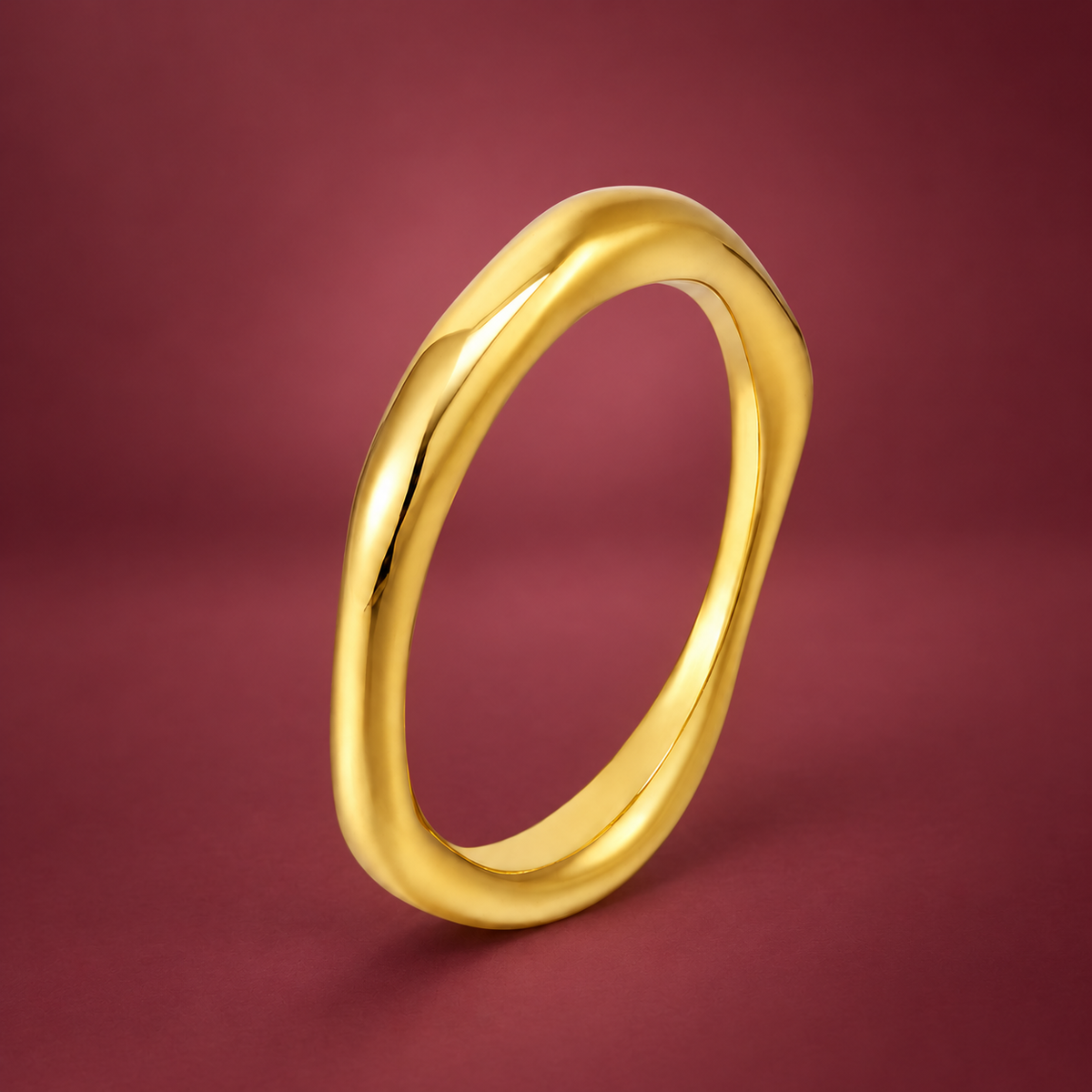 Gold-Tone Wavy Band Ring — muted burgundy background