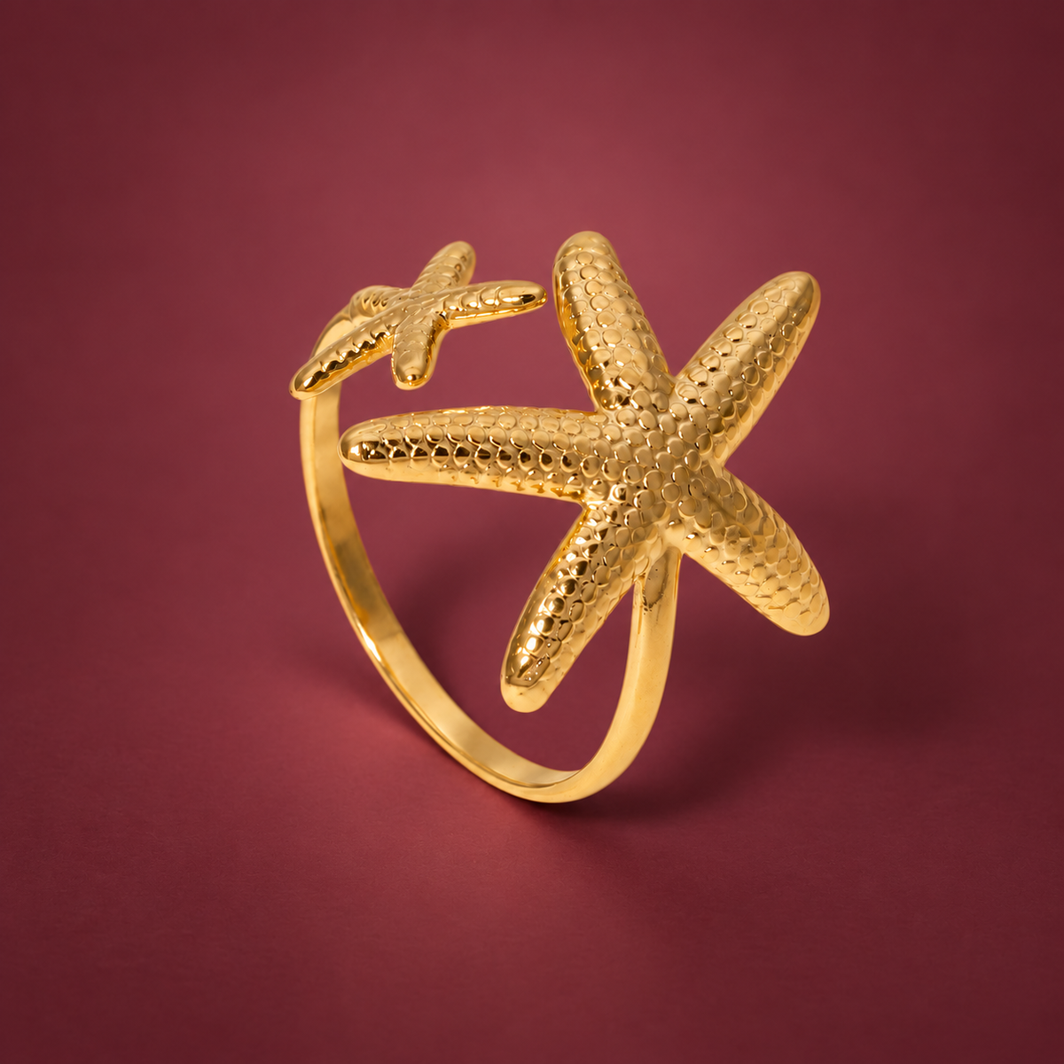 Gold-Tone Starfish Open Ring — muted burgundy background