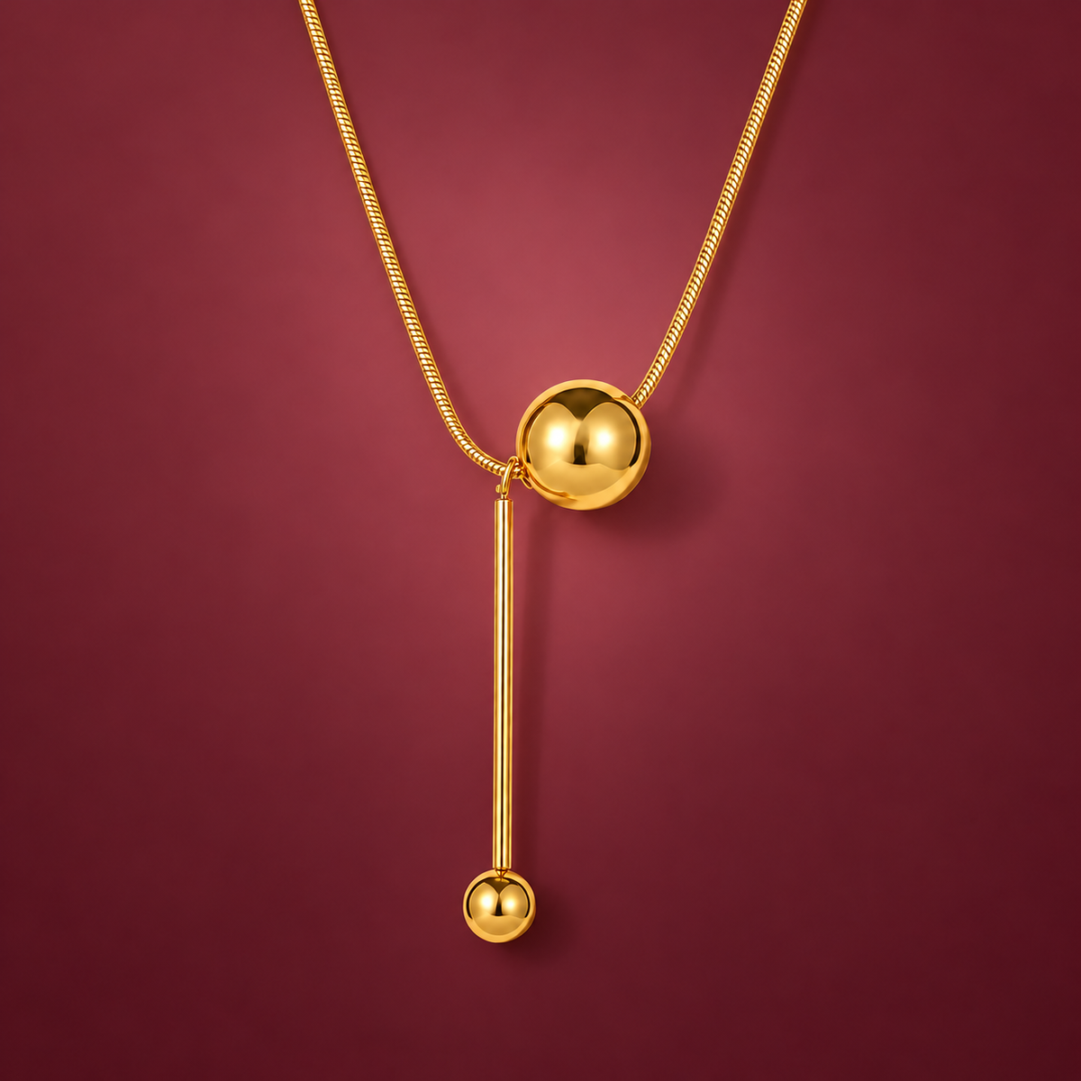 Gold-Tone Ball Y Necklace — muted burgundy background