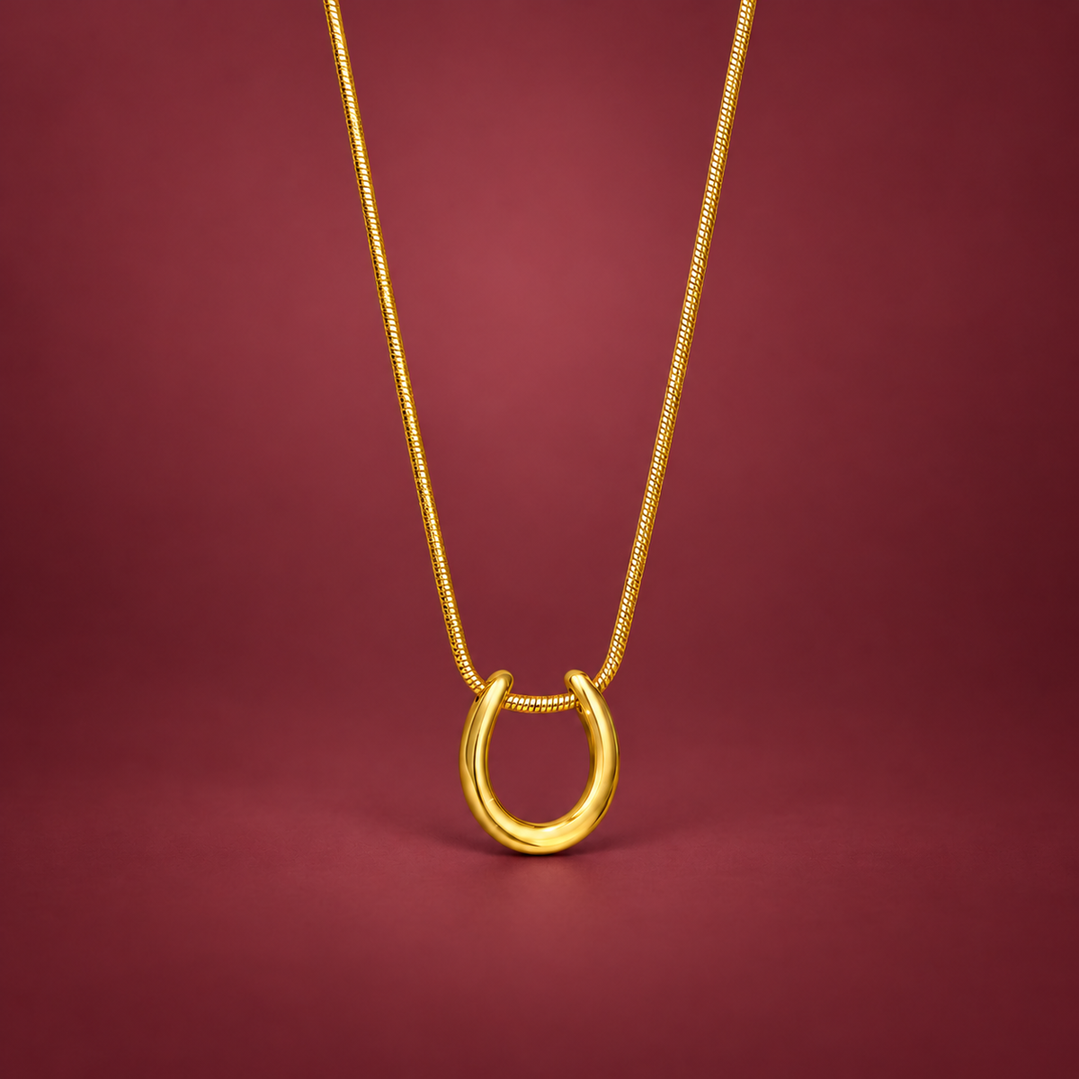 Gold-Tone Horseshoe Necklace — muted burgundy background