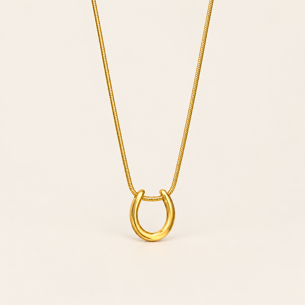 Gold Horseshoe Necklace — warm ivory background