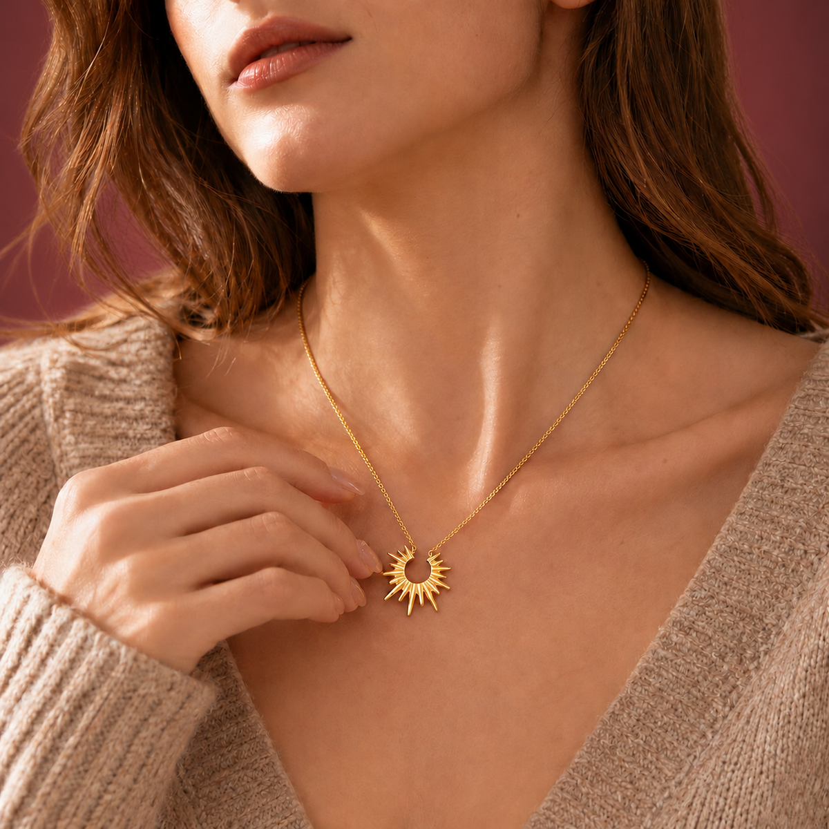 Gold-Tone Sun Pendant Necklace — muted burgundy background