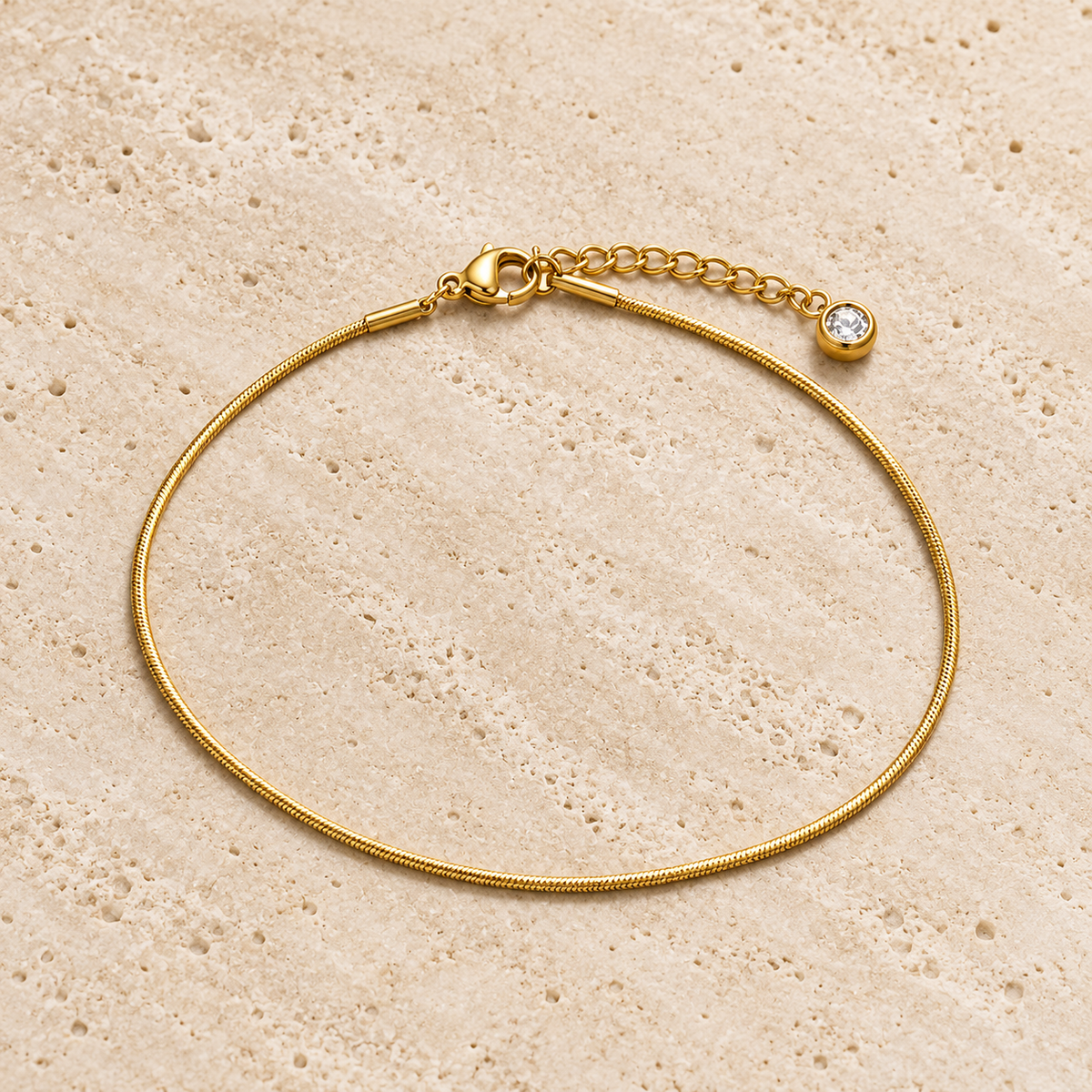 Gold Herringbone Anklet — pale beige natural stone background