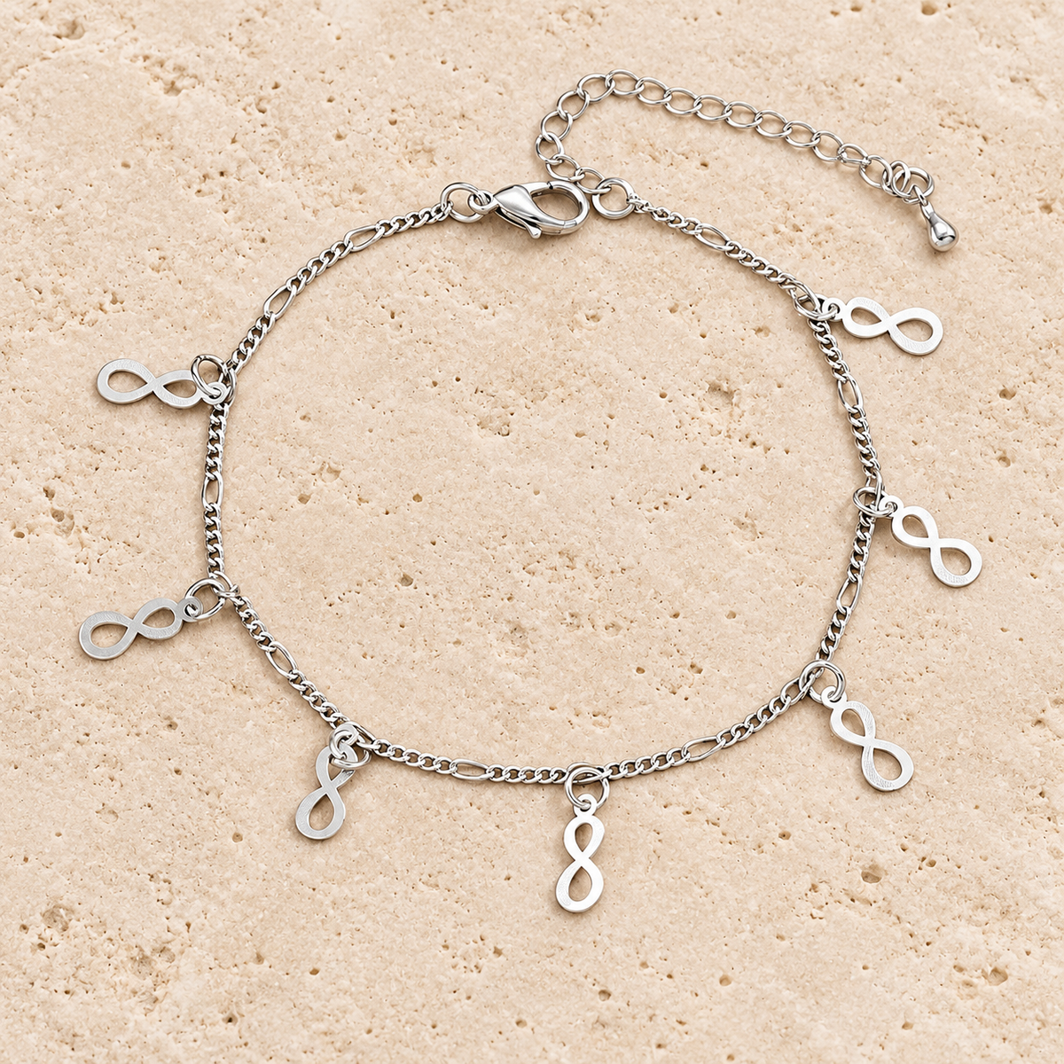 Silver Infinity Charm Anklet — pale beige natural stone background
