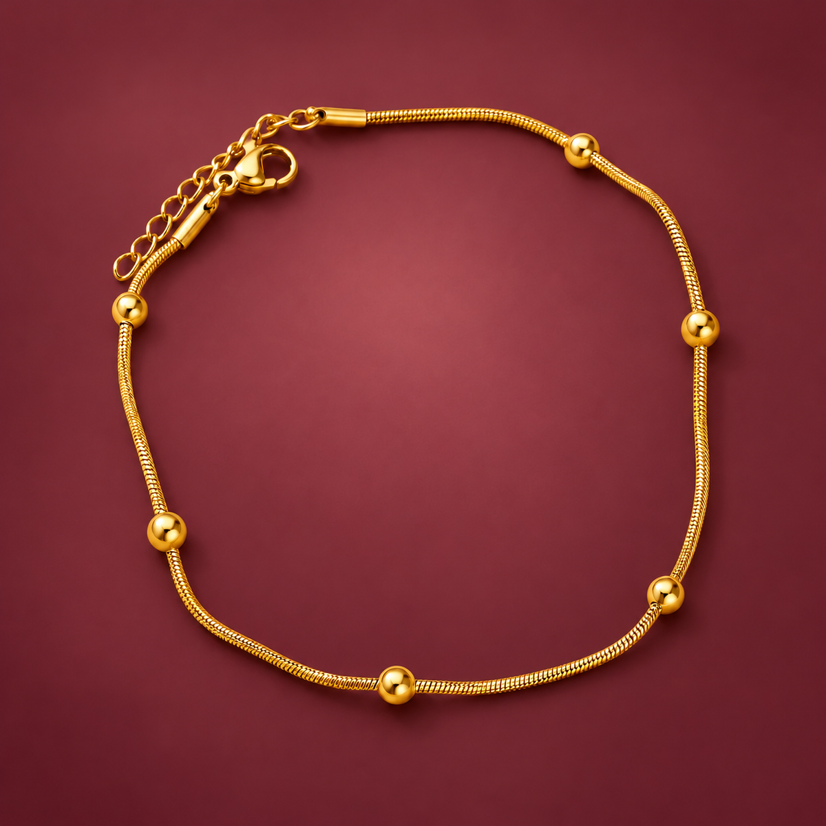 Gold-Tone Ball Anklet — muted burgundy background