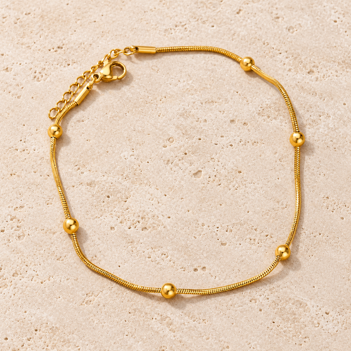 Gold Ball Anklet — pale beige natural stone background