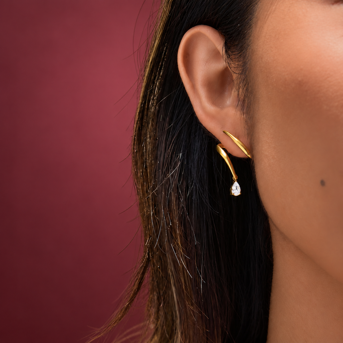 Gold-Tone Wave Crystal Earring — muted burgundy background