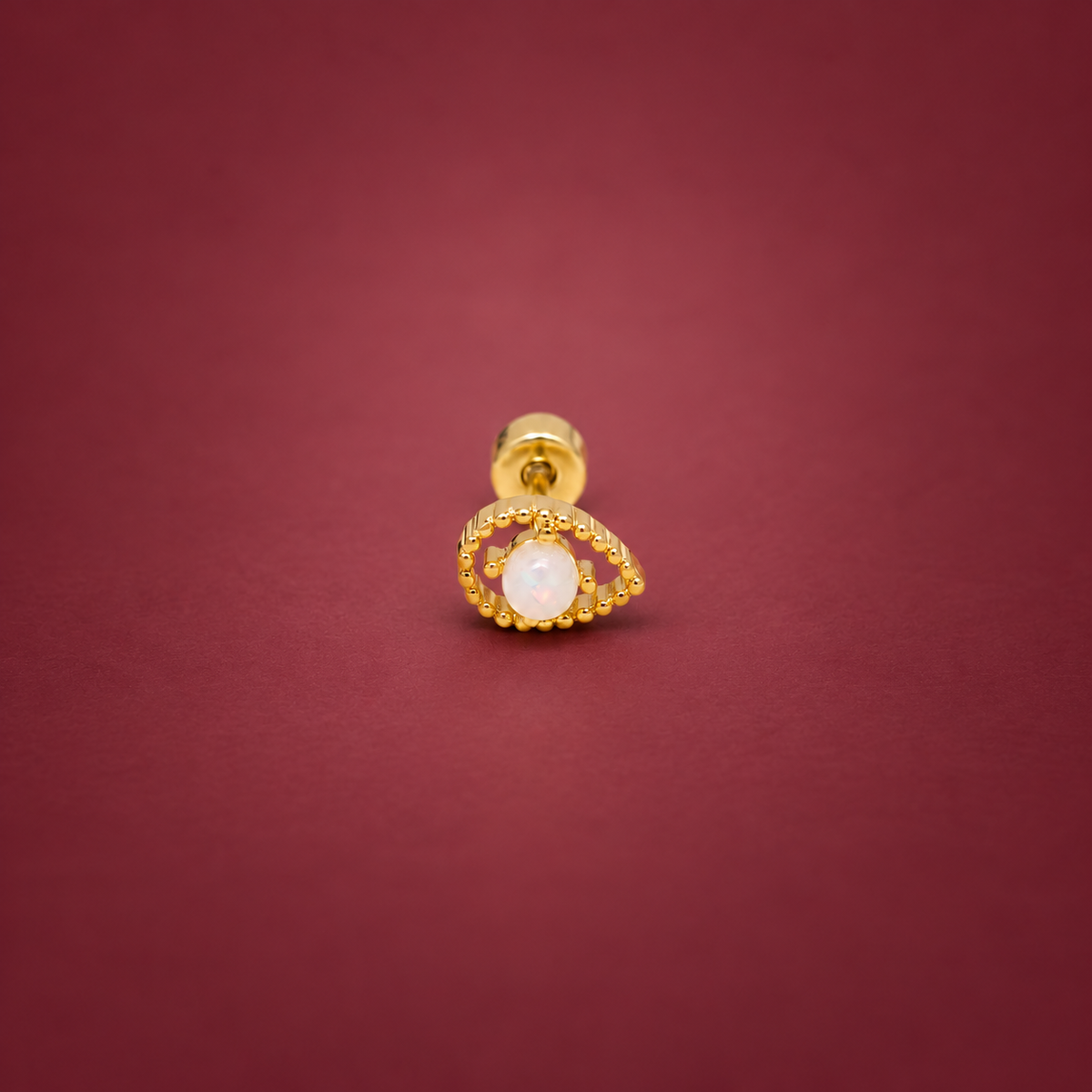 Gold-Tone Iridescent Eye Stud — muted burgundy background