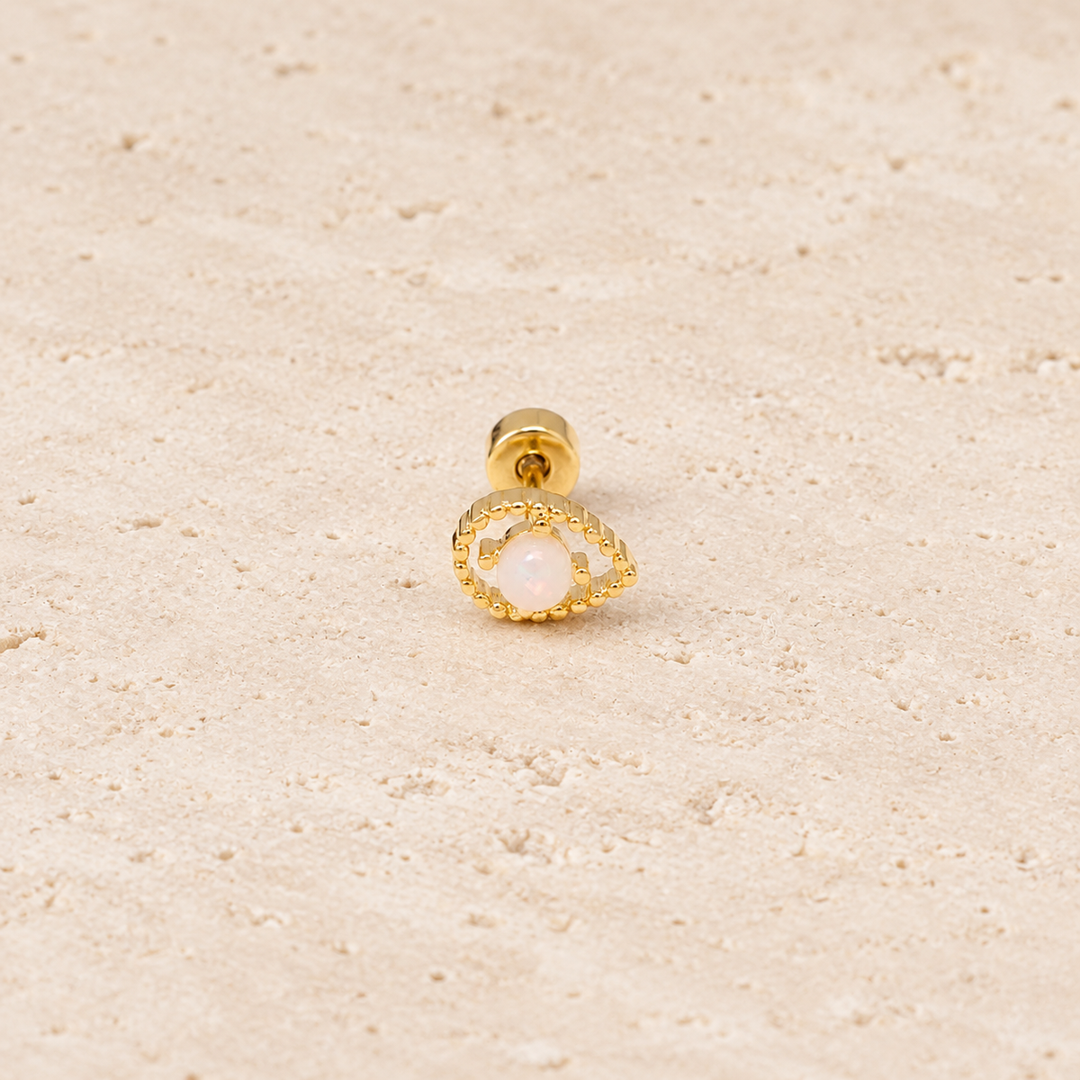 Gold-Tone Iridescent Eye Stud — pale beige natural stone background
