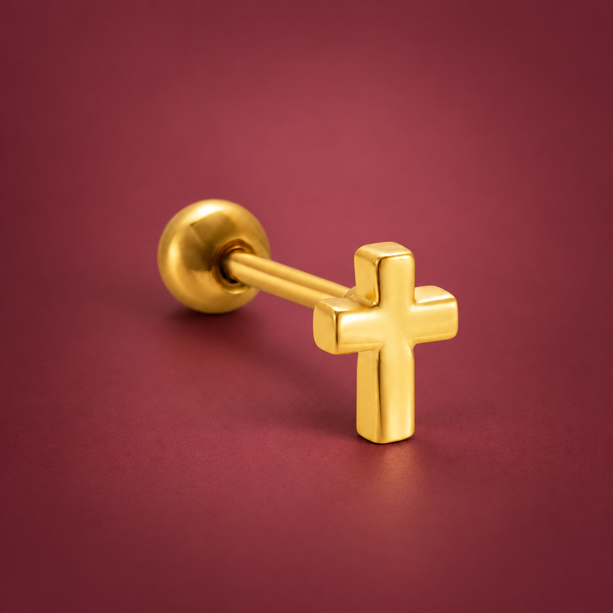 Gold-Tone Cross Ear Stud — muted burgundy background