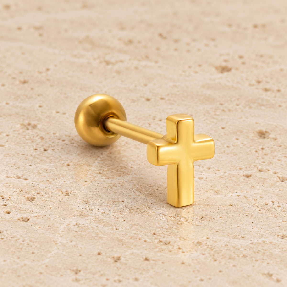 Gold Cross Ear Stud — pale beige natural stone background