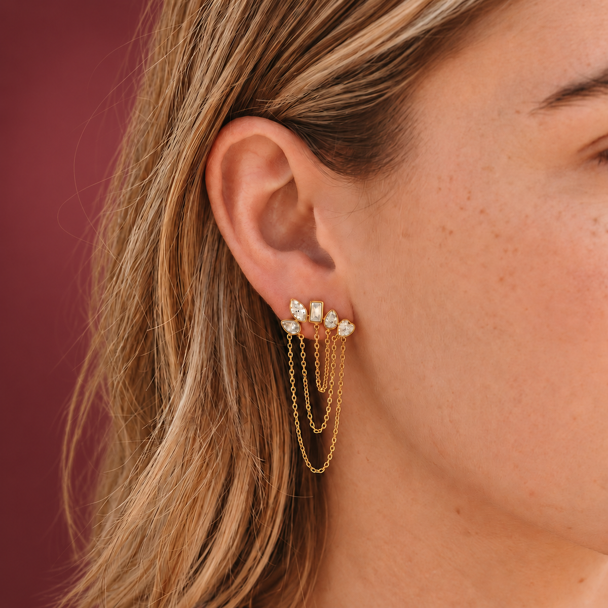Gold-Tone Crystal Cascade Earring — muted burgundy background