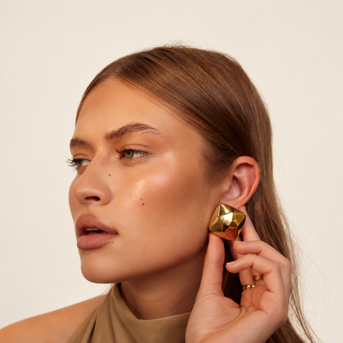 Gold Triangle Earrings gedragen tegen een warm ivoren achtergrond